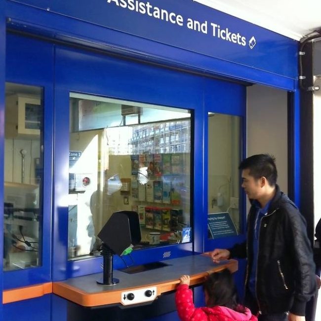 Girl-and-father-standing-at-train-ticket-booth-counter